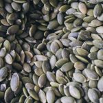 Magnesium-rich foods including pumpkin seeds, almonds, and dark chocolate on a wooden surface