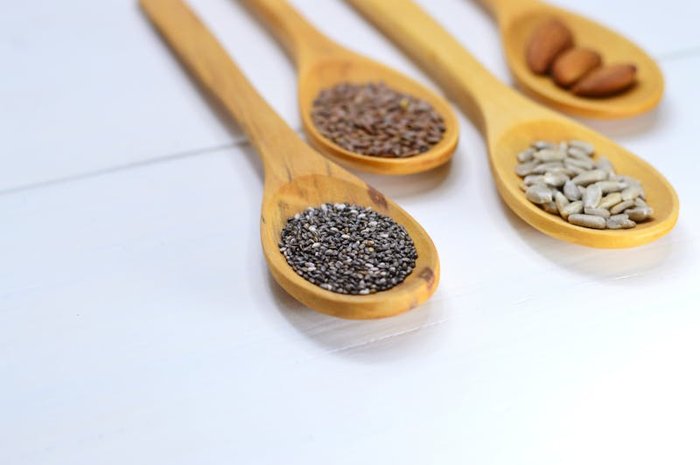 Four bowls of seeds for seed cycling flax and pumpkin for the follicular phase sesame and sunflower for the luteal phase arranged on a wooden surface representing menstrual cycle hormone balance